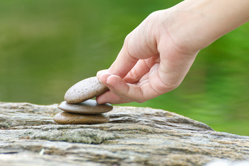 Hand put stone building a pile of zen stones