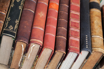 Old books with colorful leather covers lay on the counter