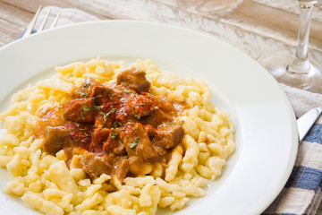 Hungarian goulash of veal with dumplings, on wooden table