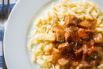 Hungarian goulash of veal with dumplings, top view, closeup