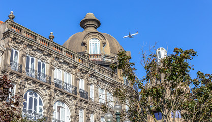 Historic building in downtown Porto with a plane flying through