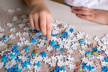 Teenager boy collects puzzles at  table