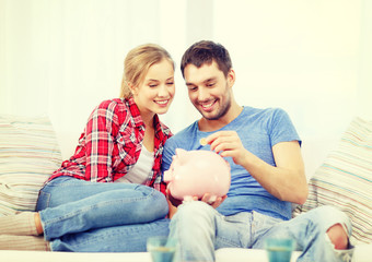 smiling couple with piggybank sitting on sofa