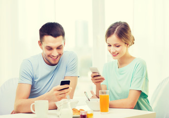 smiling couple with smartphones reading news