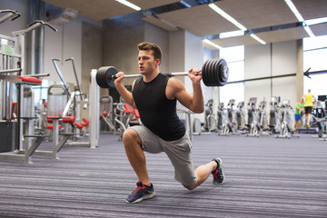 young man flexing muscles with barbell in gym
