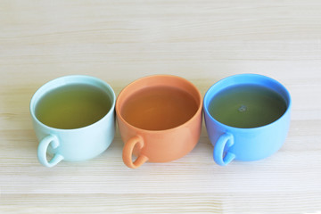 Green, orange and blue cups with green tea