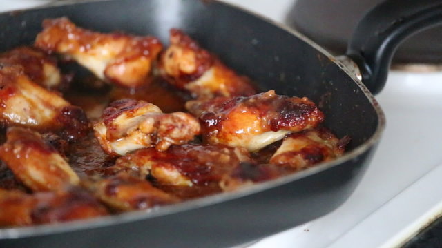 Video with delicious chicken wings and sauce in grill pan.