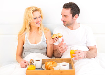 Obraz na płótnie Canvas Portrait of a couple having breakfast in bed