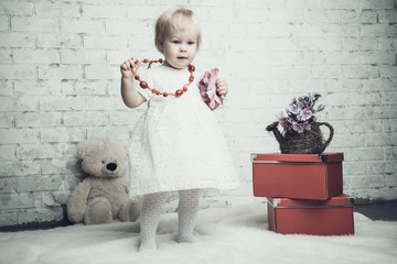 Little girl with bright red jewelery posing on brick background