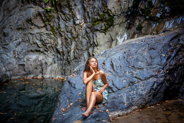 beautiful girl posing in dress at the waterfall