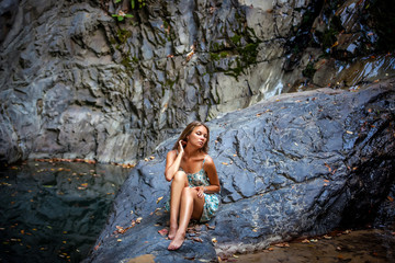 beautiful girl posing in dress at the waterfall