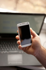Man using smartphone, close-up, notebook on the background