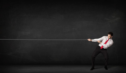 Businessman pulling rope on grey background