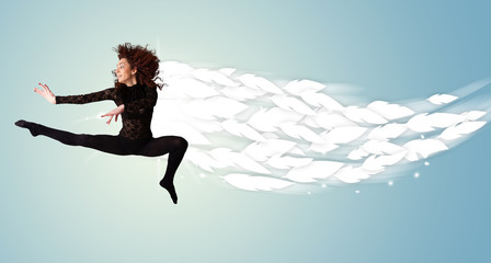 Healthy young woman jumping with feathers around her