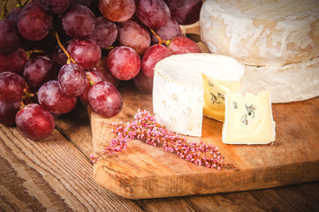 Smelly blue cheese on a wooden rustic table with grape