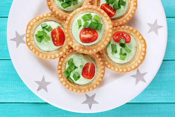 Tartlets with greens and vegetables with sauce on plate on