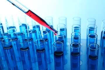Pipette adding red fluid to the one of test-tubes