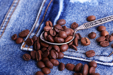 Spoon with coffee beans on ripped jeans background