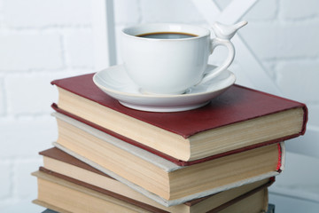 Pile of books with cup of hot drink