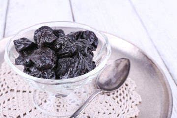 Metal tray with glass bowl of prunes, lace doily and spoon