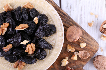 Wooden board with plate of prunes and walnuts