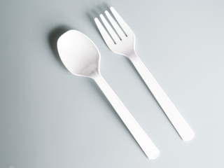 white plastic spoon and fork on gray