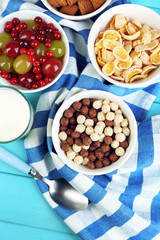 Various sweet cereals and berries in ceramic bowls and glass
