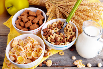 Various sweet cereals in ceramic bowl, fruits and jug with milk