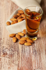 Dessert liqueur Amaretto with almond nuts, on wooden table