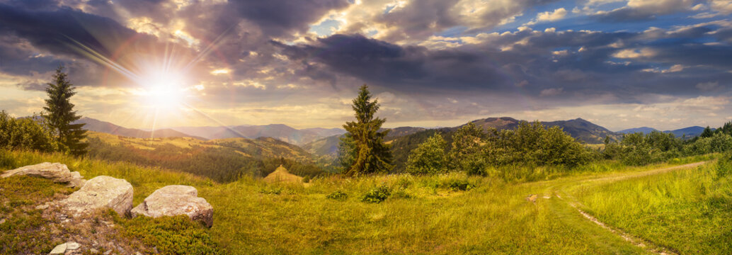 Fototapeta boulders on hillside meadow in mountain at sunset