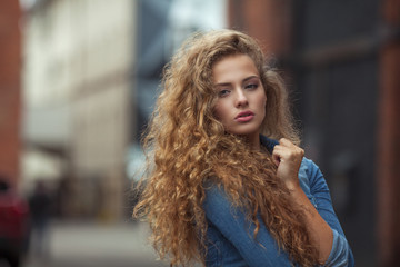 Beautiful young girl with thick long curly hair outdoors - obrazy, fototapety, plakaty