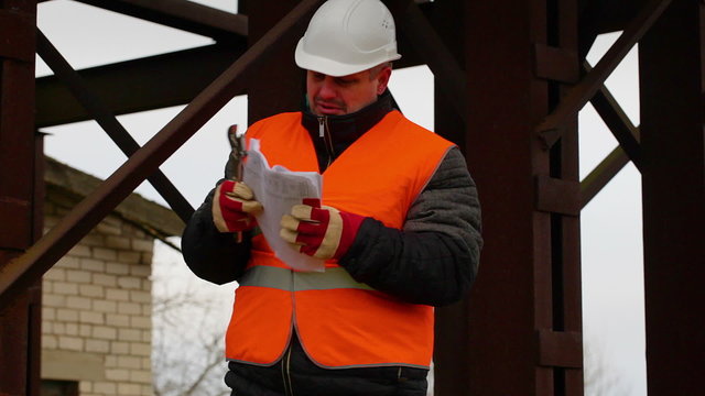 Foreman with documents and adjustable wrench in factory