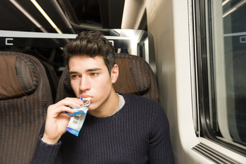 Young man on a train eating a cereal bar