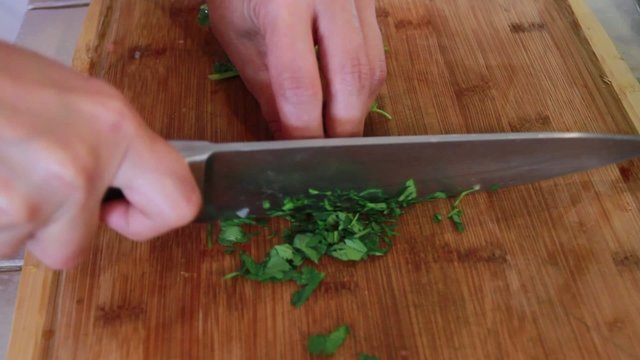 Cilantro leaves being chopped by a big knife