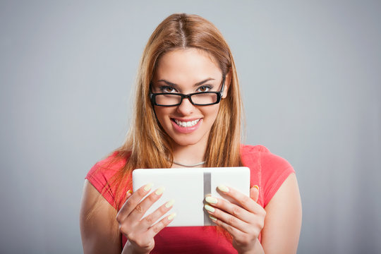 Young female using a digital tablet and smiling. Studio shot