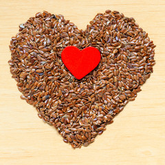 Raw flax seeds linseed heart shaped on wooden table