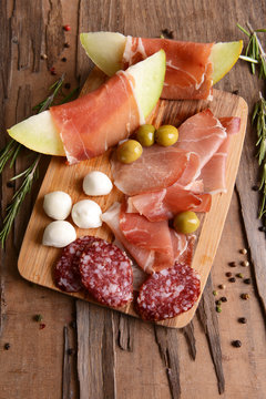 Delicious melon with prosciutto on table close-up