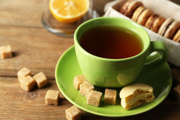 Colorful macaroons with cup of tea on wooden background