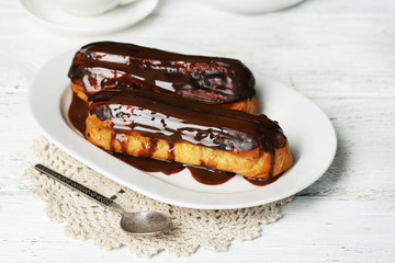 Tasty eclairs on wooden table, close up