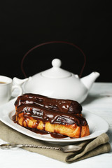 Tasty eclairs and pot of tea