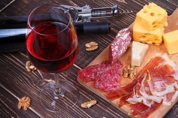Glass and bottle of wine, cheese and prosciutto. Still life