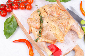Fresh raw chicken prepared for roast with thyme and tomatoes