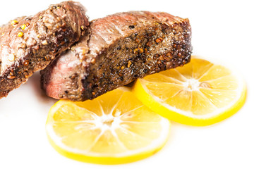 Sliced roasted meat with slices of lemon closeup