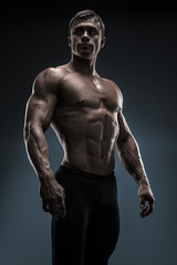 Fototapeta na wymiar Handsome muscular bodybuilder posing over black background