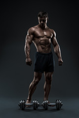 Fototapeta na wymiar Stunning muscular bodybuilder posing over black background