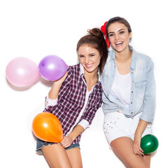 Fototapeta na wymiar Two happy girls smiling and holding colored balloons