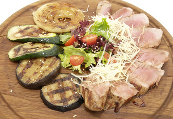 meat roasted on a grill with vegetables on a wooden plate