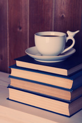 Old books and cup of coffee on table