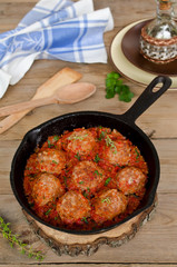 Fried meatballs with tomato sauce and spices in frying pan