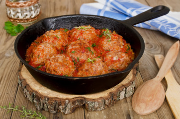 Fried meatballs with tomato sauce and spices in frying pan